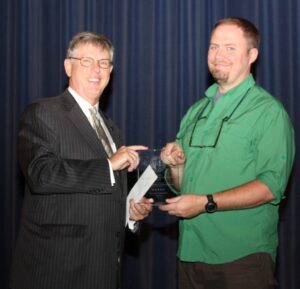 President Robin Capehart presents award to Dr. Zachary Loughman.