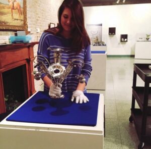 Olivia Best is shown working with the Oglebay Family silver.